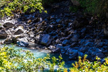 Turkuaz mavi ve yeşil nehir buharı ve köprü taşlı şelale hanı. Çimen ağaçları, doğa ve dağ manzarası. Alplerde uçan Landeck Tyrol Avusturya..