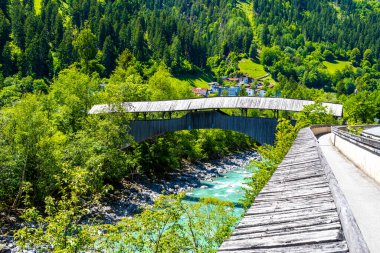Turkuaz mavi ve yeşil nehir buharı ve köprü taşlı şelale hanı. Çimen ağaçları, doğa ve dağ manzarası. Alplerde uçan Landeck Tyrol Avusturya..