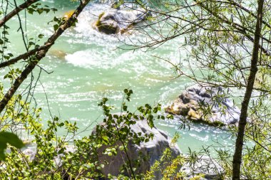 Turkuaz mavi ve yeşil nehir buharı ve köprü taşlı şelale hanı. Çimen ağaçları, doğa ve dağ manzarası. Alplerde uçan Landeck Tyrol Avusturya..