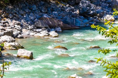Turkuaz mavi ve yeşil nehir buharı ve köprü taşlı şelale hanı. Çimen ağaçları, doğa ve dağ manzarası. Alplerde uçan Landeck Tyrol Avusturya..