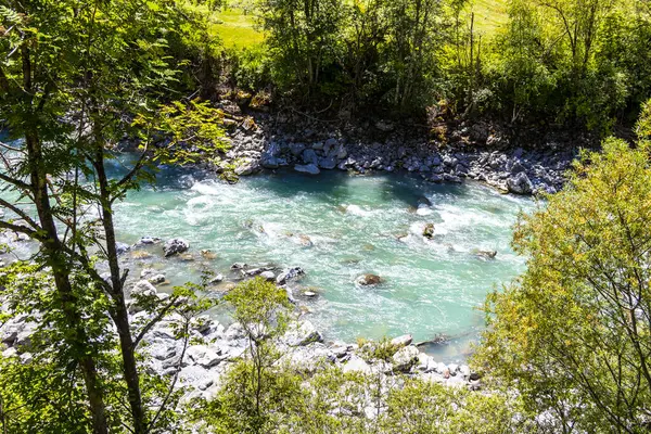 Turkuaz mavi ve yeşil nehir buharı ve köprü taşlı şelale hanı. Çimen ağaçları, doğa ve dağ manzarası. Alplerde uçan Landeck Tyrol Avusturya..
