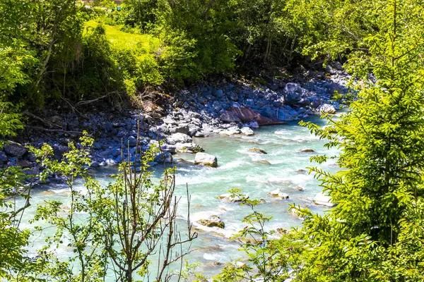 Turkuaz mavi ve yeşil nehir buharı ve köprü taşlı şelale hanı. Çimen ağaçları, doğa ve dağ manzarası. Alplerde uçan Landeck Tyrol Avusturya..