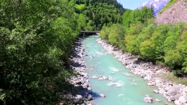 Turkuaz mavi ve yeşil nehir buharı ve taşlı şelale hanı. Çimen ağaçları ve Alpler 'deki dağ manzarası. Landeck Tyrol Avusturya..