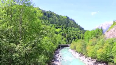 Turkuaz mavi ve yeşil nehir buharı ve taşlı şelale hanı. Çimen ağaçları ve Alpler 'deki dağ manzarası. Landeck Tyrol Avusturya..