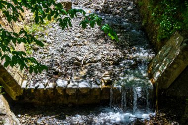 Turkuaz mavi ve yeşil nehir buharı ve taşlı şelale hanı. Çimen ağaçları ve Alpler 'deki dağ manzarası. Uçamayan Landeck Tyrol Avusturya..