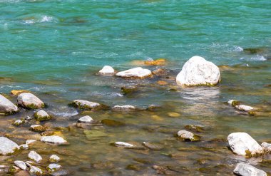 Turkuaz mavi ve yeşil nehir buharı ve taşlı şelale hanı. Çimen ağaçları ve Alpler 'deki dağ manzarası. Uçamayan Landeck Tyrol Avusturya..