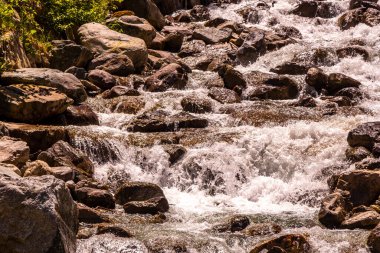 Turkuaz mavi ve yeşil nehir buharı ve taşlı şelale hanı. Çimen ağaçları ve Alpler 'deki dağ manzarası. Uçamayan Landeck Tyrol Avusturya..
