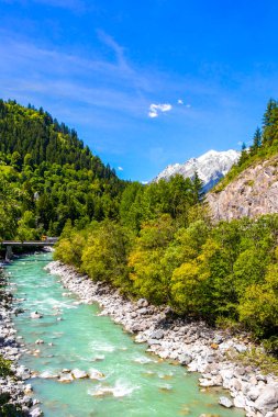 Turkuaz mavi ve yeşil nehir buharı ve taşlı şelale hanı. Çimen ağaçları ve Alpler 'deki dağ manzarası. Uçamayan Landeck Tyrol Avusturya..