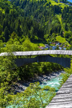 Turkuaz mavi ve yeşil nehir buharı ve taşlı şelale hanı. Çimen ağaçları ve Alpler 'deki dağ manzarası. Uçamayan Landeck Tyrol Avusturya..