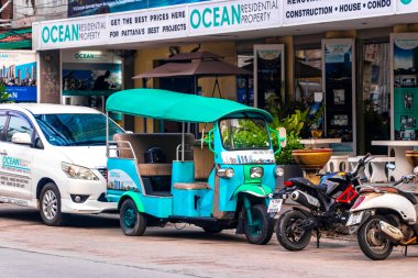Pattaya Chon Buri Tayland 25. Ekim 2018 Turkuaz klasik tuk tuk otomobil taksisi Pattaya Bang Lamung Amphoe Buri Tayland 'da arabaların ve motosikletlerin arasına park edilmiş..