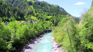 Turkuaz mavi ve yeşil nehir buharı ve köprü taşlı şelale hanı. Çimen ağaçları, doğa ve dağ manzarası. Alplerde uçan Landeck Tyrol Avusturya..