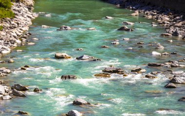 Turkuaz mavi ve yeşil nehir buharı ve taşlı şelale hanı. Alplerdeki dağların arasındaki çimen ağaçları. Landeck District Landeck Tyrol Austria..
