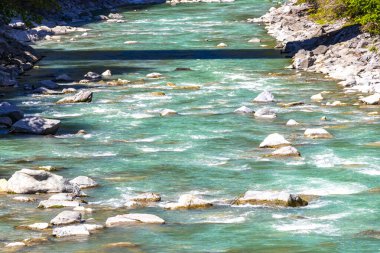 Turkuaz mavi ve yeşil nehir buharı ve taşlı şelale hanı. Alplerdeki dağların arasındaki çimen ağaçları. Landeck District Landeck Tyrol Austria..
