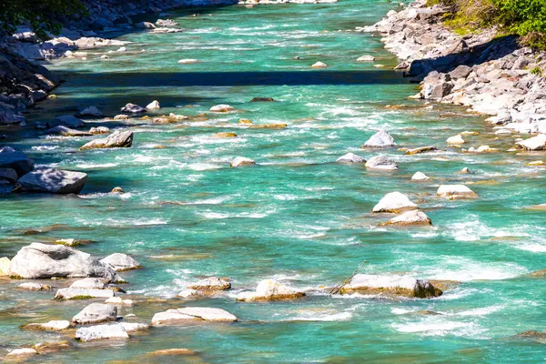Turkuaz mavi ve yeşil nehir buharı ve taşlı şelale hanı. Alplerdeki dağların arasındaki çimen ağaçları. Landeck District Landeck Tyrol Austria..