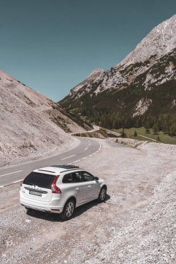 Imst Tyrol Avusturya 31. Mayıs 2025 Dağ ve Alp Dağları 'ndaki beyaz SUV araç kamyonu Alpler Tyrol Avusturya' da kayalık doğa ve mavi gökyüzü ile dağ ve kaya zirveleri.