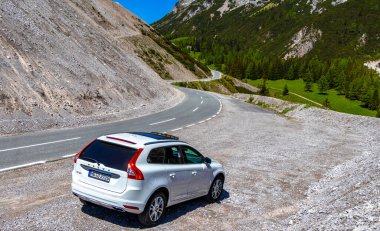 Imst Tyrol Avusturya 31. Mayıs 2025 Dağ ve Alp Dağları 'ndaki beyaz SUV araç kamyonu Alpler Tyrol Avusturya' da kayalık doğa ve mavi gökyüzü ile dağ ve kaya zirveleri.