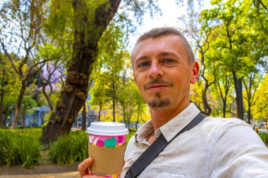 Yakışıklı turist içkileri, kahveyi alıp Centro Historico City Mexico 'daki bir parkta fincana götürür..