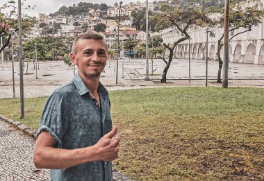 Yakışıklı erkek turist ve gezgin Arcos da Lapa köprüsü ve şehir sokakları kemerli mavi bulutlu gökyüzü arabaları ve Rio de Janeiro Brezilya 'daki insanlar.