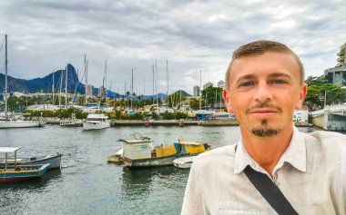 Yakışıklı turist, Urca Village sahil ve sahil gezintisinde özçekim yapıyor. Rio de Janeiro Brezilya 'da rıhtım iskelesi yatları ve tekneleri var..