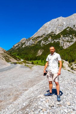 Dağlarda ve Alp Dağları 'nda kamerası olan yakışıklı bir turist. Dağlar, kayalar, orman köknar ağaçları ve Alpler' de mavi gökyüzü olan manzaralar..