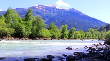 Turkuaz mavi ve yeşil nehir buharı ve taşlı şelale hanı. Çimen ağaçları, doğa ve dağ manzarası Alpler Zams Landeck Tyrol Avusturya 'da..