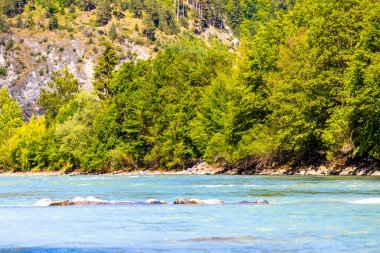 Turkuaz mavi ve yeşil nehir buharı ve taşlı şelale hanı. Çimen ağaçları, doğa ve dağ manzarası Alpler Zams Landeck Tyrol Avusturya 'da..