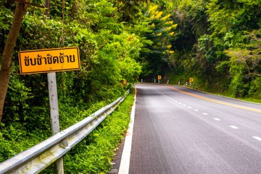 Güney Asya 'daki Chiang Mai Amphoe Mueang Mai Tayland' da sarı trafik işareti olan tropikal ormanda yol..