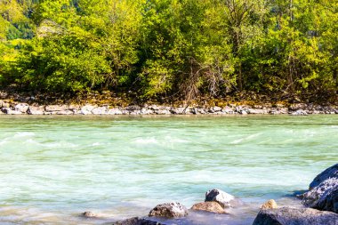 Turkuaz mavi ve yeşil nehir buharı ve taşlı şelale hanı Alpler Zams Landeck Tyrol Avusturya 'daki dağlar arasındaki çimen ağaçları..