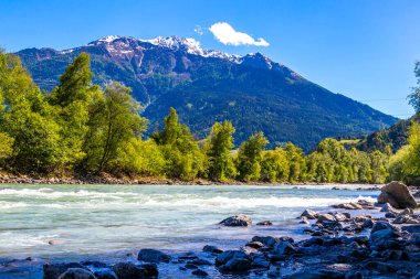 Turkuaz mavi ve yeşil nehir buharı ve taşlı şelale hanı. Çimen ağaçları, doğa ve dağ manzarası Alpler Zams Landeck Tyrol Avusturya 'da..