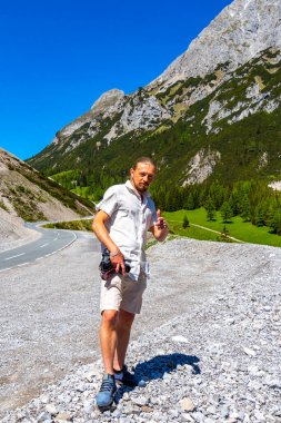 Dağlarda ve Alp Dağları 'nda kamerası olan yakışıklı bir turist. Dağlar, kayalar, orman köknar ağaçları ve Alpler' de mavi gökyüzü olan manzaralar..
