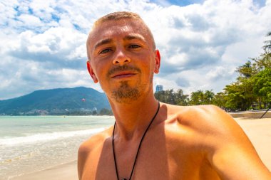 Güneydoğu Asya 'da Patong Sahili' nde turkuaz mavi su ve beyaz kumla gezen yakışıklı turist Kathu Bölgesi Phuket Adası Bölgesi Güney Tayland.