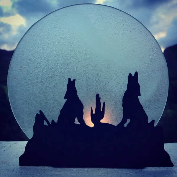 Siluetli, uluyan kurtların fotoğrafı. Mum ışığı ve alacakaranlık gökyüzü.