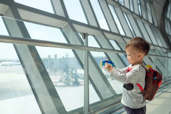 Stock image Little traveler, cute smiling little Asian 2 years old toddler boy child having fun playing with airplane toy while waiting for his flight at gate in terminal at airport, Traveling with kid concept