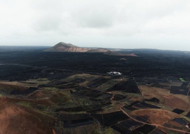 Lanzarote, Kanarya Adaları 'ndaki volkanların havadan çekilmiş fotoğrafı. Volkanik karanlık dağların ve yüksek irtifadaki kraterlerin insansız hava aracıyla çekilmiş fotoğrafı. Yukarıdan Lanzarote 'nin güzel manzarası.