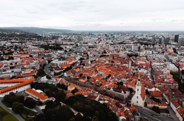 Slovakya 'nın havadan görünüşü - Bratislava' nın arka planında eski bir kasaba. Bratislava şehrinin panoramik manzarası kasvetli ve karanlık gün batımında turuncu çatılar ve güzel caddelerle.