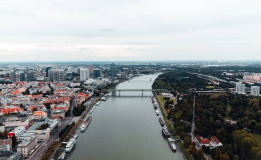 Slovakya 'nın başkentinin havadan görünüşü - Bratislava eski kenti ve arkasında köprü bulunan Tuna Nehri. Bratislava şehrinin panoramik manzarası karamsar gün batımı çatıları ve Tuna nehri ile.