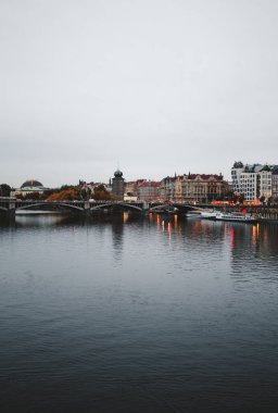 Prag 'ın tarihi bölümünün dikey görüntüsü ve Vltava Nehri önplanda - akşam çekilmiş. Sonbahar zamanı Vltava Nehri 'ndeki köprü.