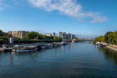 Gezinti güvertesi, demirli gemiler ve modern ofis binalarıyla Paris 'teki Seine Nehri.