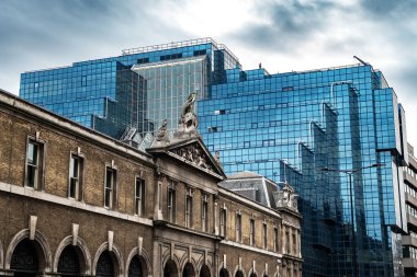 Londra, İngiltere 'nin finans bölgesinde mavi camlı yüzüyle modern ofis binasının önündeki eski tarihi bina.