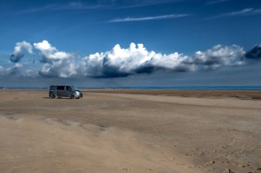 Galler 'deki düşük dalgalı bir limandaki kumsal plajında kamp aracı.