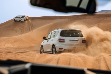 Dubai, Birleşik Arap Emirlikleri - 01 Temmuz 2021: Kum çölünde yarış. Yarış yarışı çölü. Araba toz bulutlarıyla yoldan çıkıyor. Yabanda engellerle yarışan off road aracı