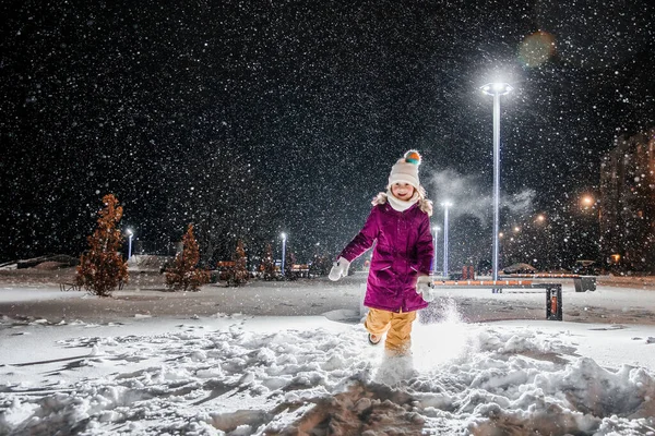 Stock image A little girl is very happy with the first snow on a cold winter night. Falling realistic natural snowflakes on a black backgraund.