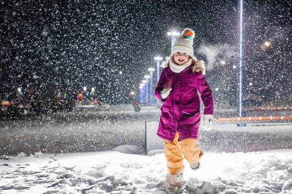 stock image A little girl is very happy with the first snow on a cold winter night. Falling realistic natural snowflakes on a black backgraund.