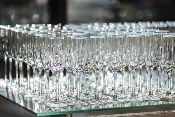 Group of empty and transparent champagne glasses in a restaurant. Clean glasses on a table prepared by the bartender for champagne. Catering for the event preparation, empty glasses for drink.