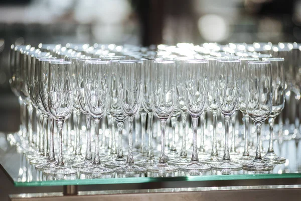 Group of empty and transparent champagne glasses in a restaurant. Clean glasses on a table prepared by the bartender for champagne. Catering for the event preparation, empty glasses for drink.