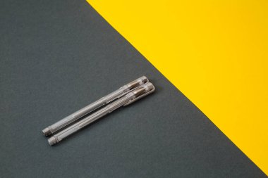 Sarı ve gri arka planda sarı ve gri jel kalemler.