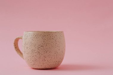 Empty ceramic cup on pink background, copy space.