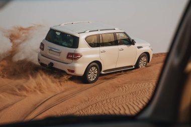 Dubai, Birleşik Arap Emirlikleri - 01 Temmuz 2021: Kum çölünde yarış. Yarış yarışı çölü. Araba toz bulutlarıyla yoldan çıkıyor. Yabanda engellerle yarışan off road aracı