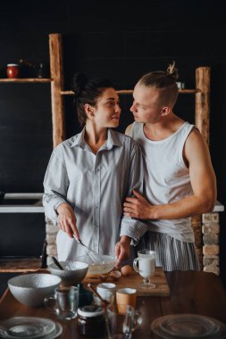 Aşık genç bir çift mutfakta birlikte sağlıklı yemekler pişiriyor. Gülerek ve konuşarak.