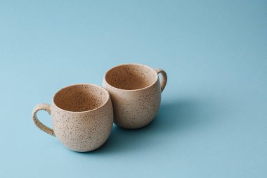 Mavi arkaplanda iki porselen boş bardak, boşluğu kopyala